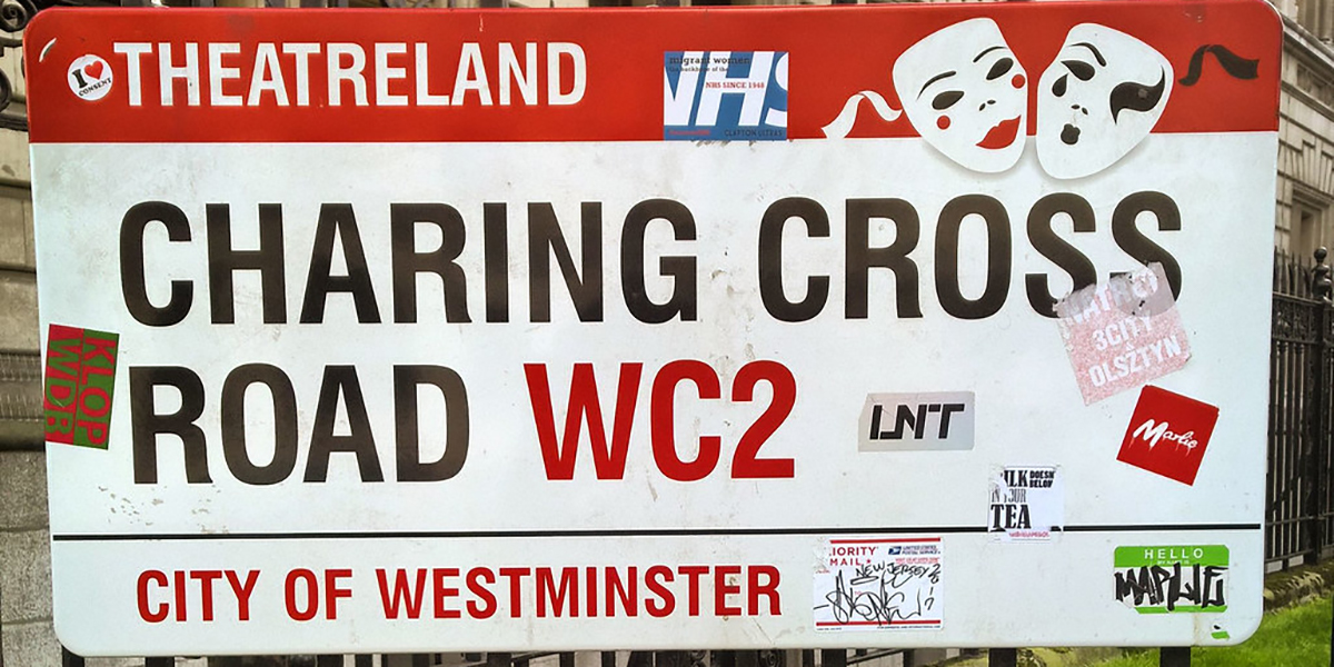 A sign reading "Charming Cross Road WC2," indicating directions to the TKTS Booth from Charing Cross Underground station.