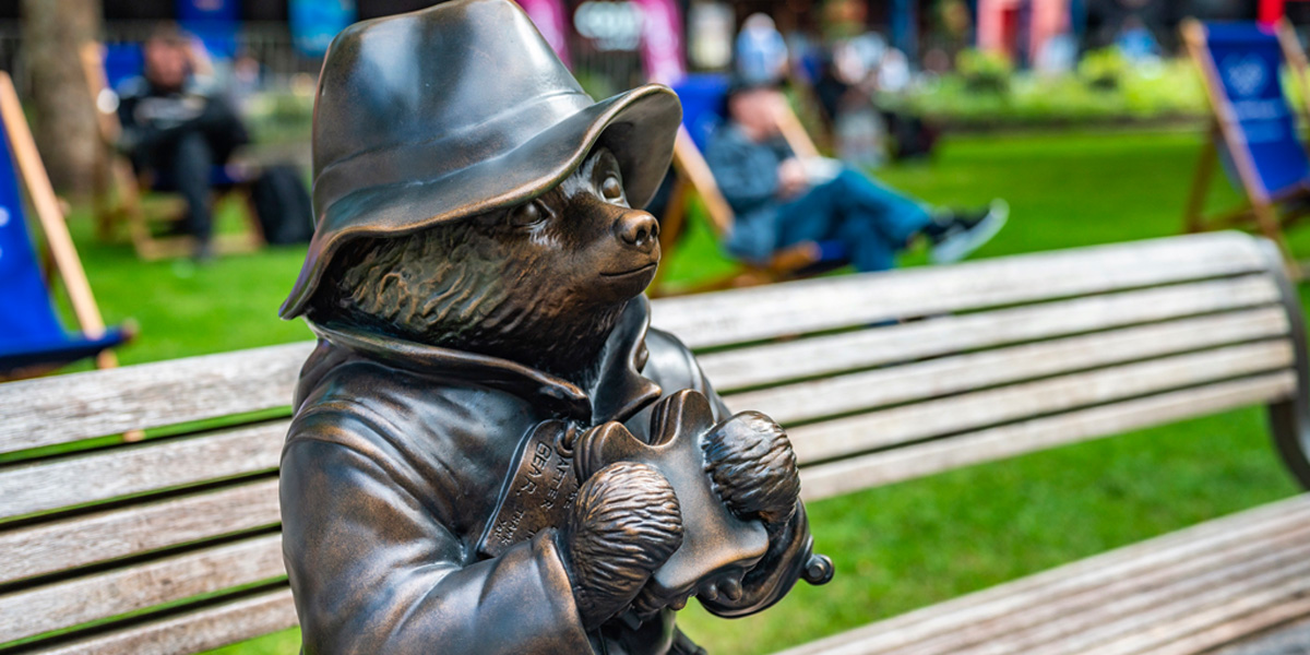 Paddington bear statue sat on a bench eating a marmalade sandwich